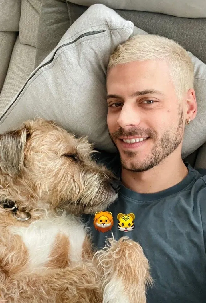 a man laying on top of a couch next to a dog with his head on the pillow