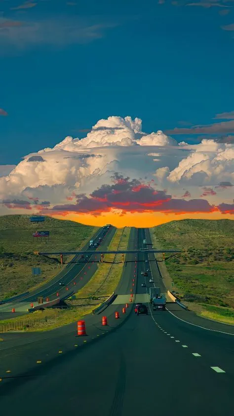 the sun is setting on an empty highway in the middle of nowhere, with cars driving down it