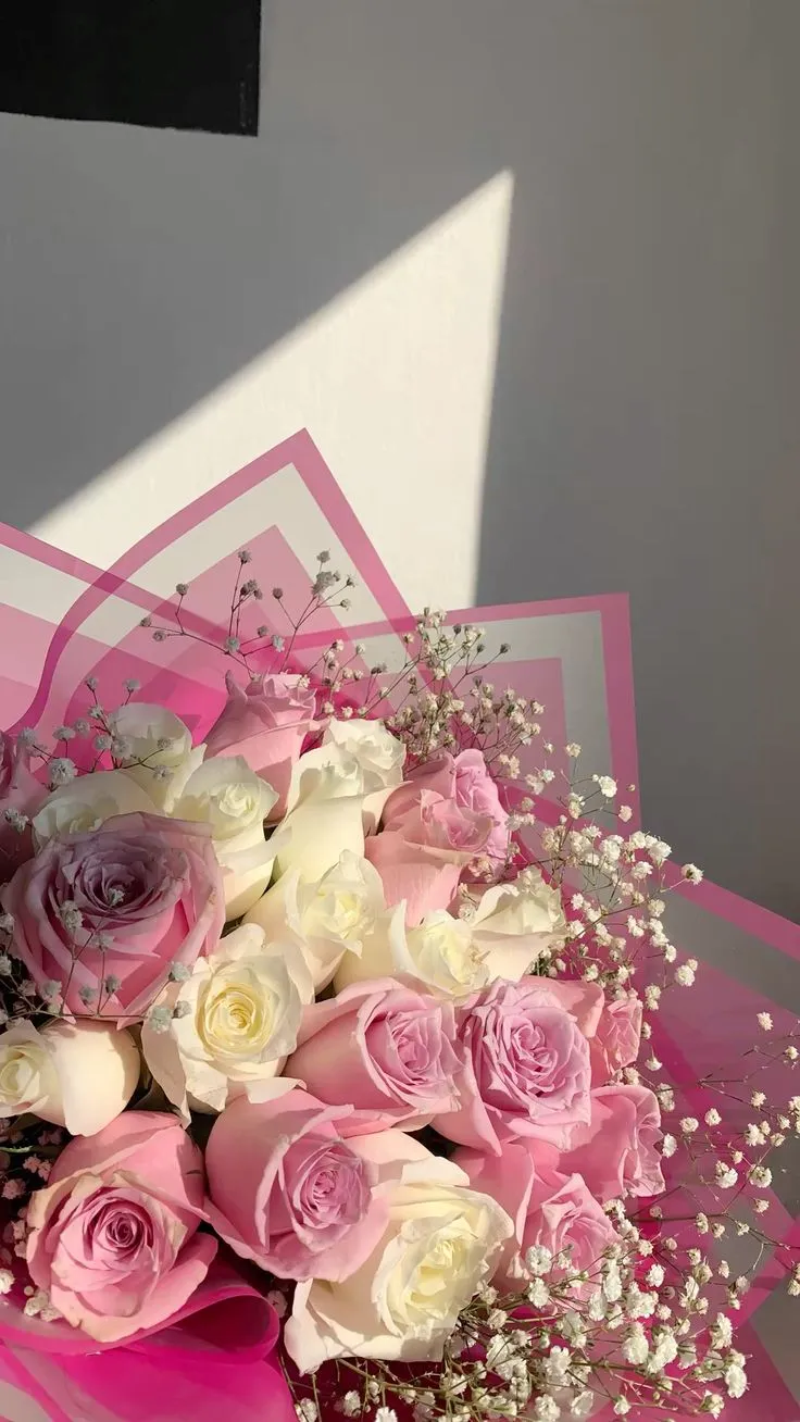 a bouquet of pink and white roses sitting on top of a table