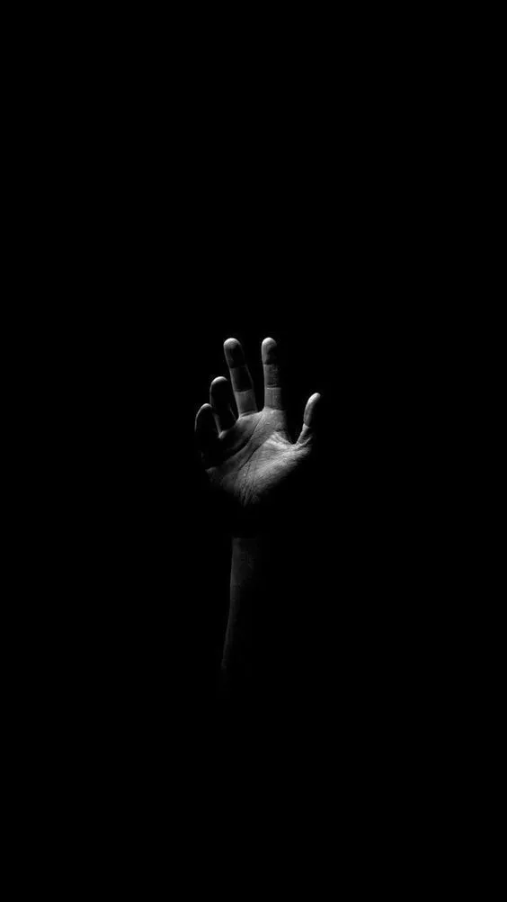 a person's hand reaching up into the dark