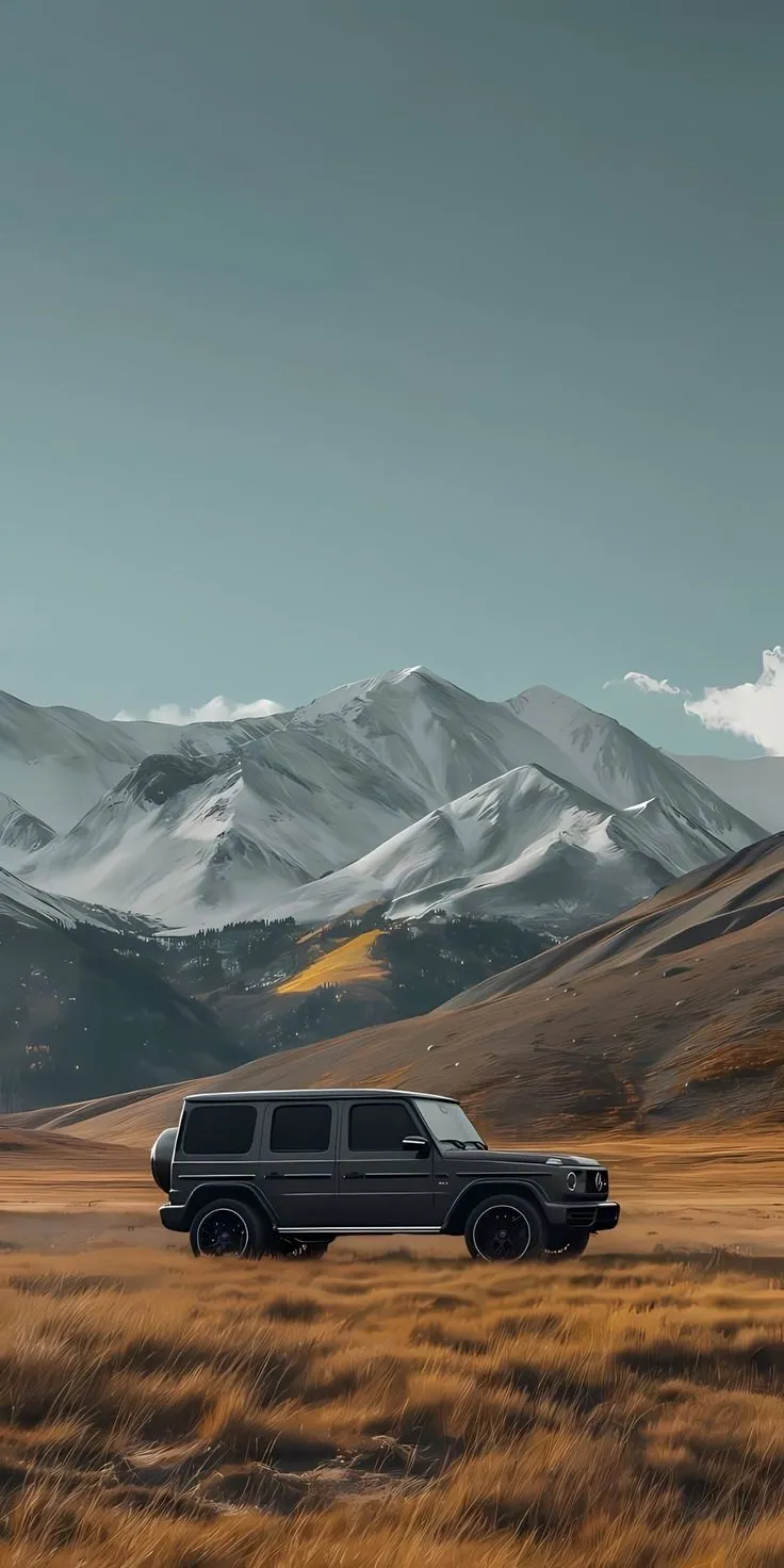 two vehicles are parked in an open field with mountains in the background