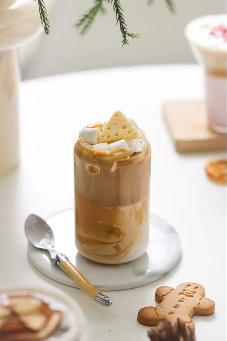 there is a cup of hot chocolate with marshmallows in it and cookies on the side