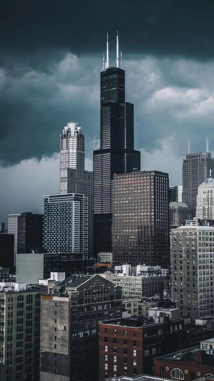 the city skyline is shown with dark clouds in the sky