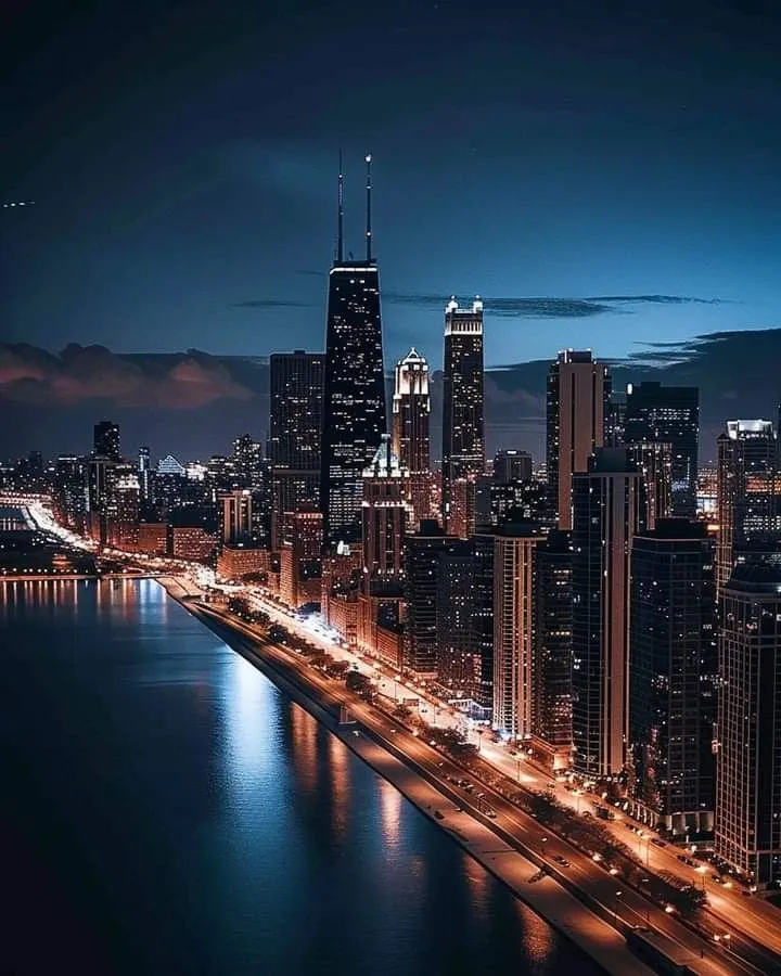an aerial view of a city at night with the lights on and skyscrapers lit up