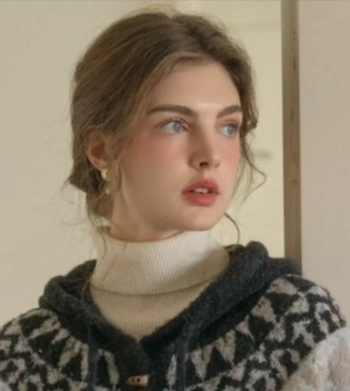 a young woman with blue eyes wearing a black and white sweater looking off into the distance