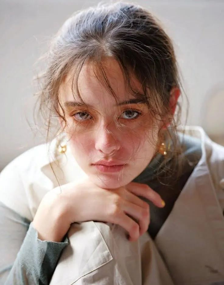 a close up of a person with a serious look on their face and hand near her chin