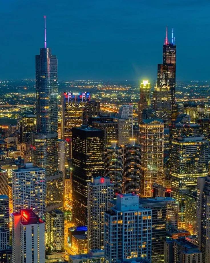 the city lights shine brightly at night in this aerial view from above, with skyscrapers and other high rise buildings