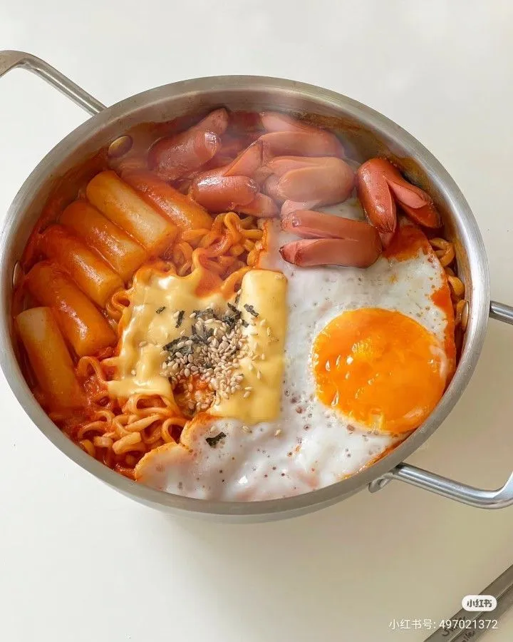 a pan filled with pasta, eggs and sausages on top of a white table