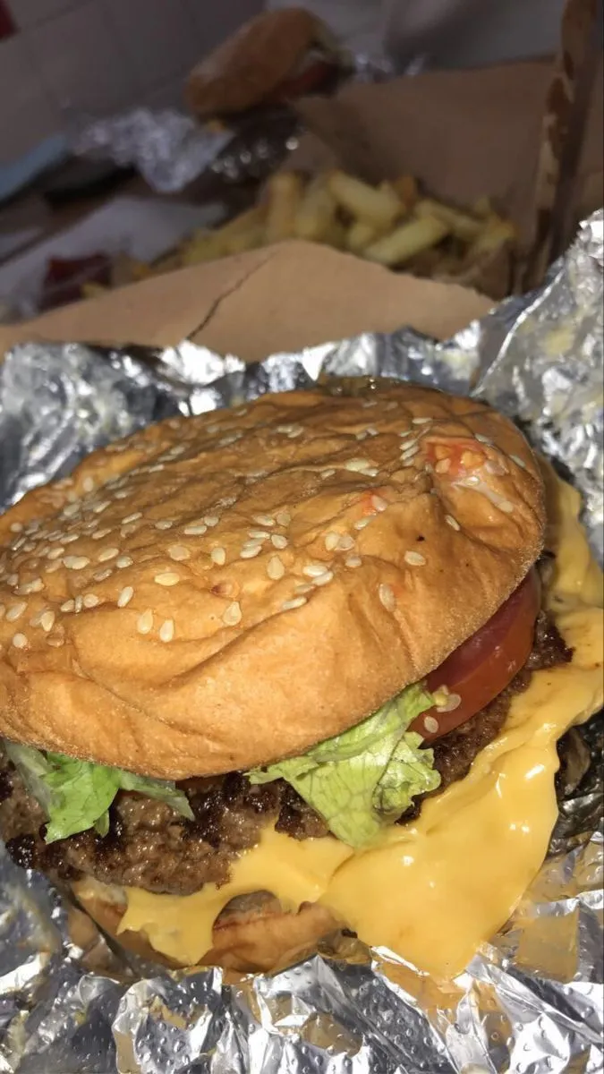 a cheeseburger with lettuce and tomato on it is sitting in foil