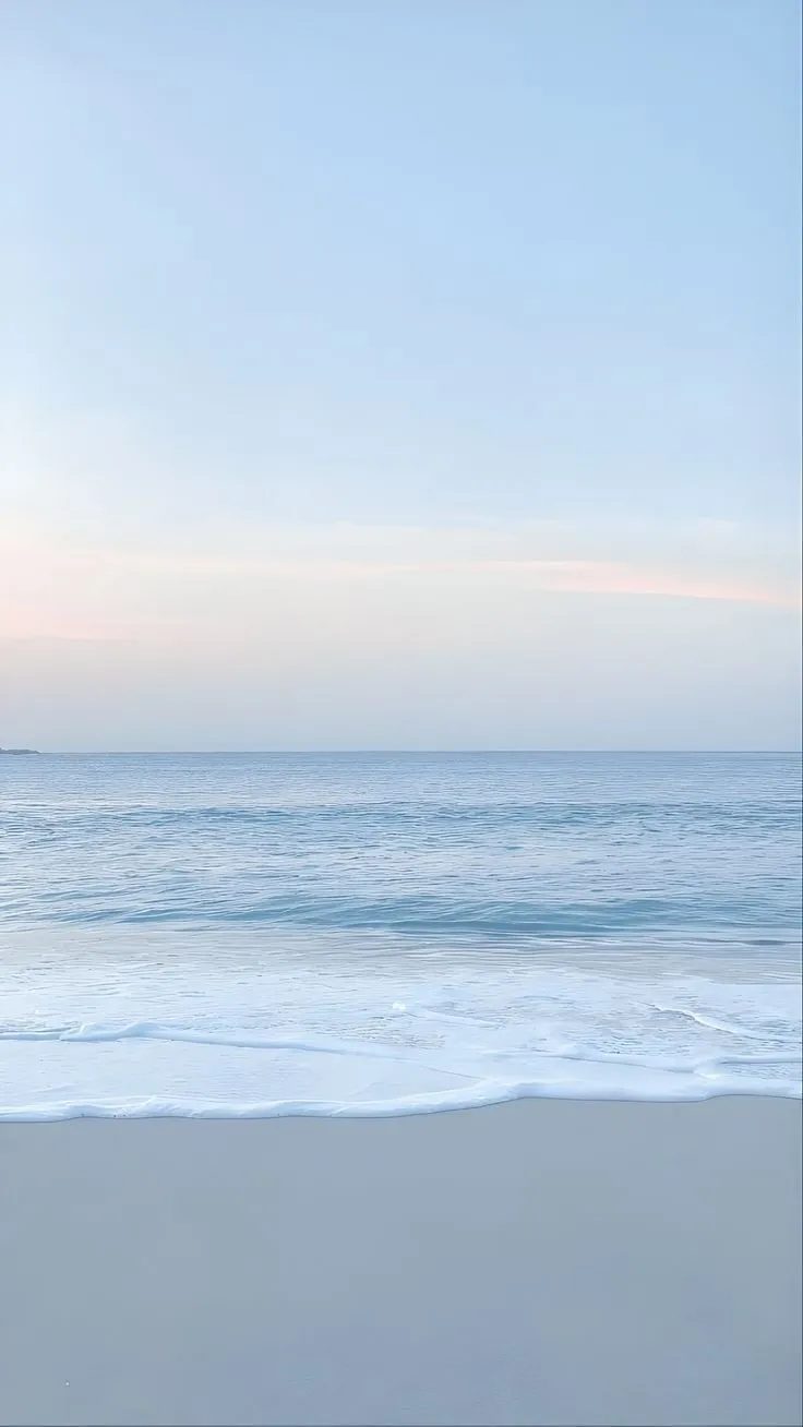 an empty beach with waves coming in to shore and the sky is blue, white and pink