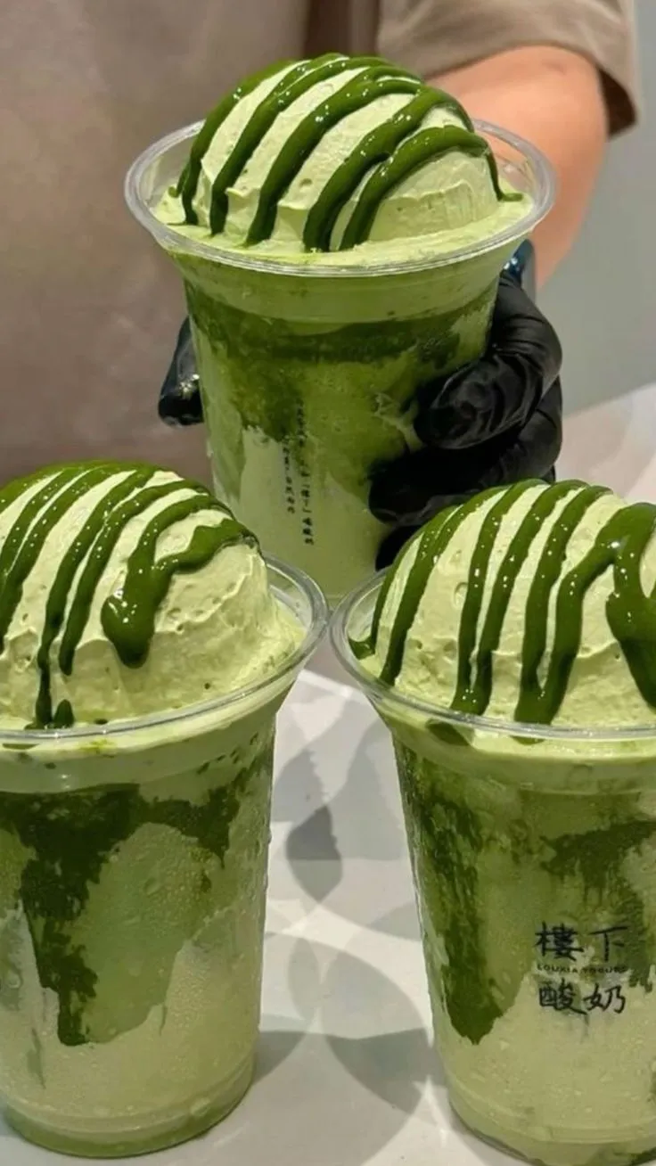 three cups filled with green ice cream on top of a table