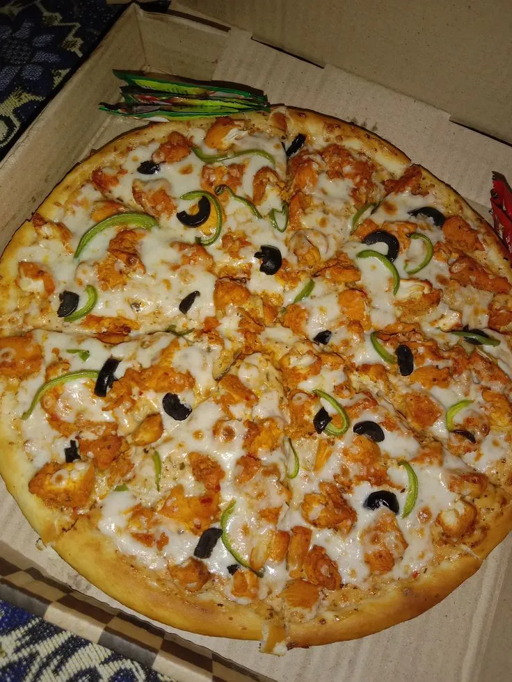 a large pizza in a box with toppings on the top and side pieces missing