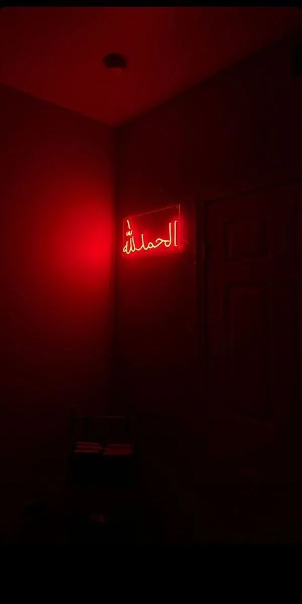 a red neon sign that is on the side of a wall in a dark room