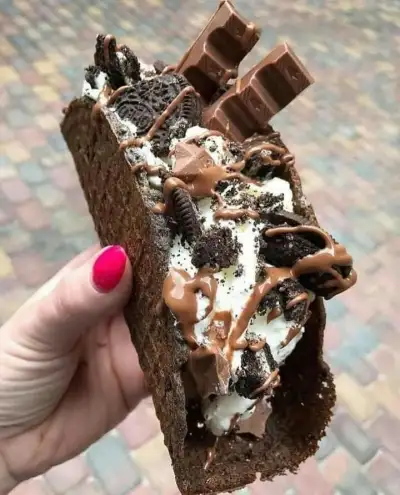 a hand holding a piece of chocolate ice cream sandwich