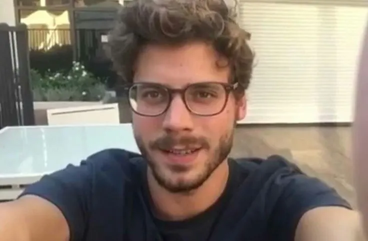 a man with glasses is smiling and looking at the camera while sitting in front of a table