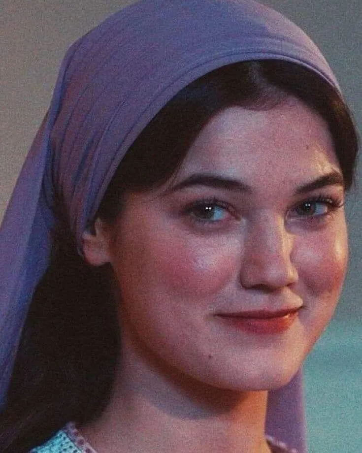 a woman wearing a purple turban and smiling at the camera with her eyes closed