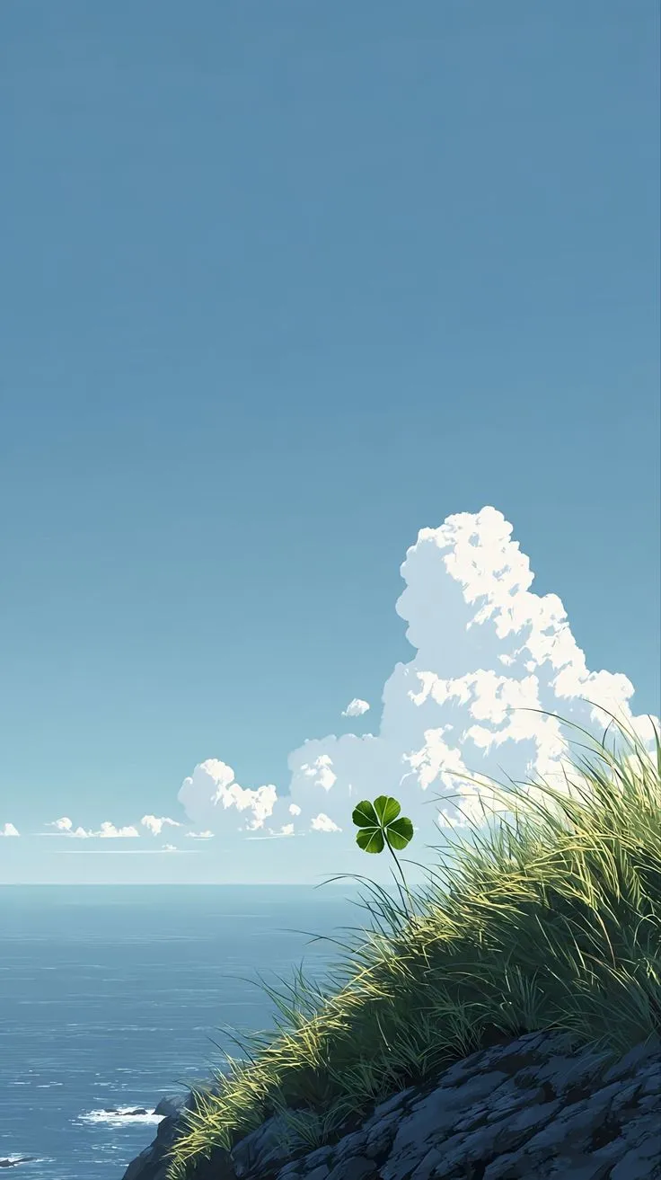 the grass is growing on top of the hill by the water and clouds in the sky