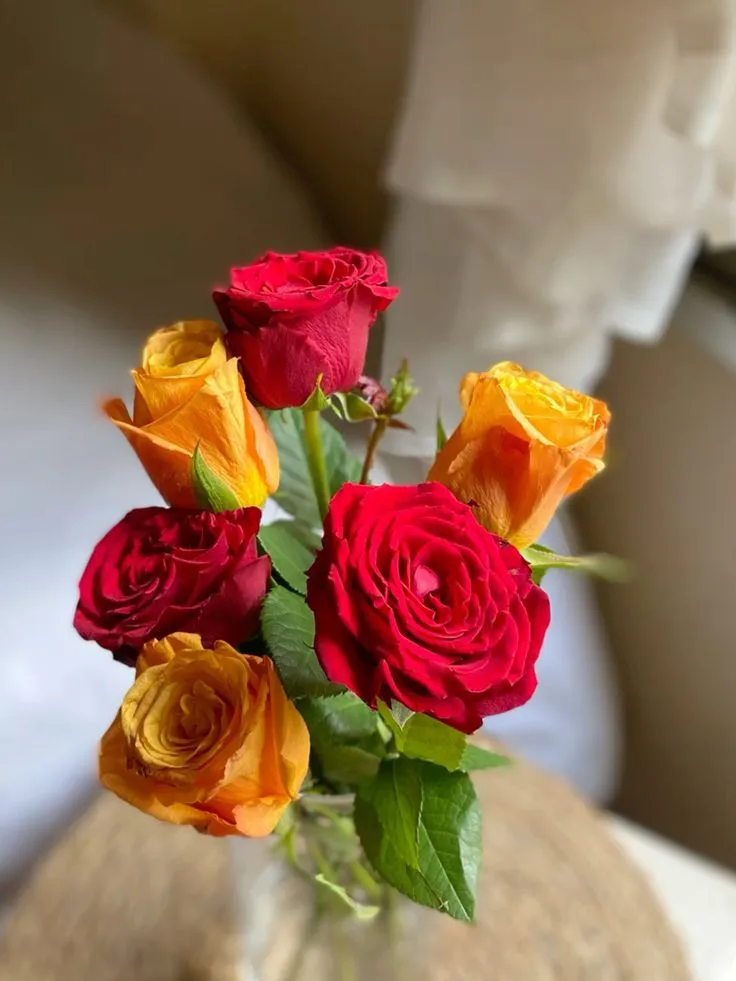 a vase filled with red and yellow roses