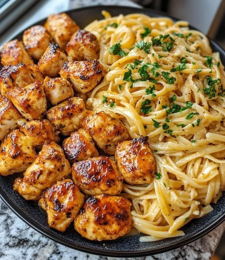 a plate full of pasta, chicken and shrimp with parsley on the side next to a glass window