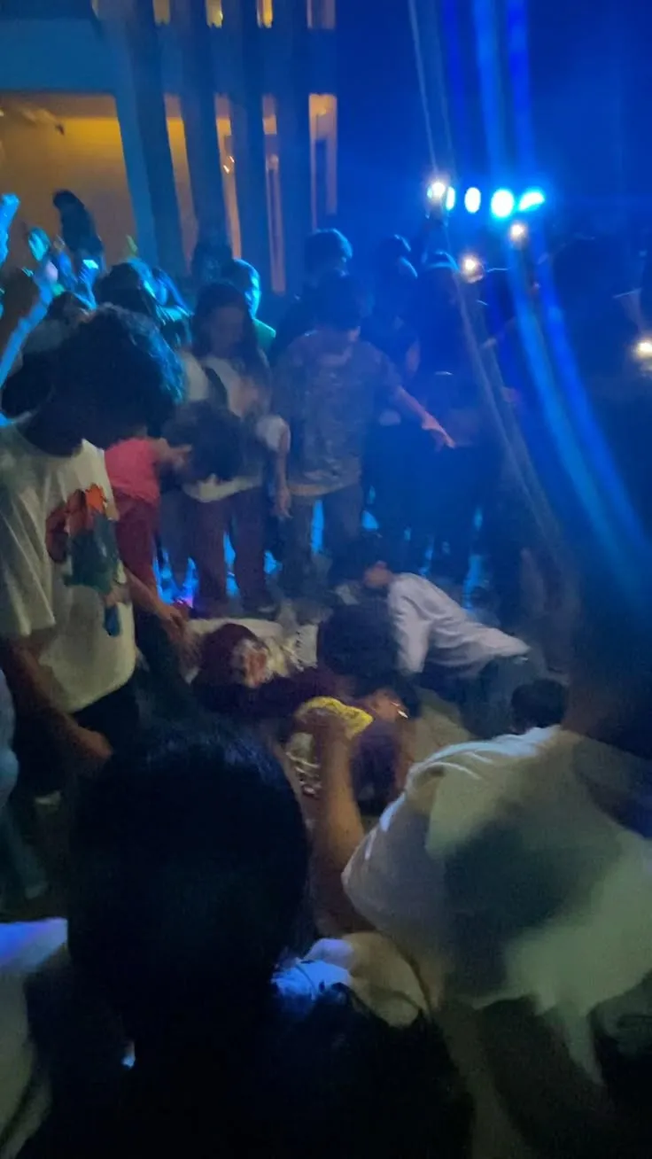 a group of people standing around each other in a room with blue lights on the walls