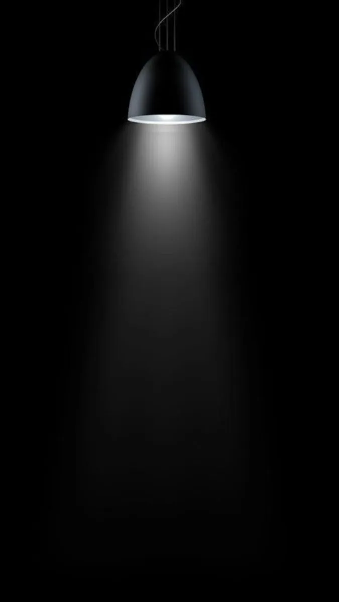a black and white photo of a light in the dark with an object hanging from it's side