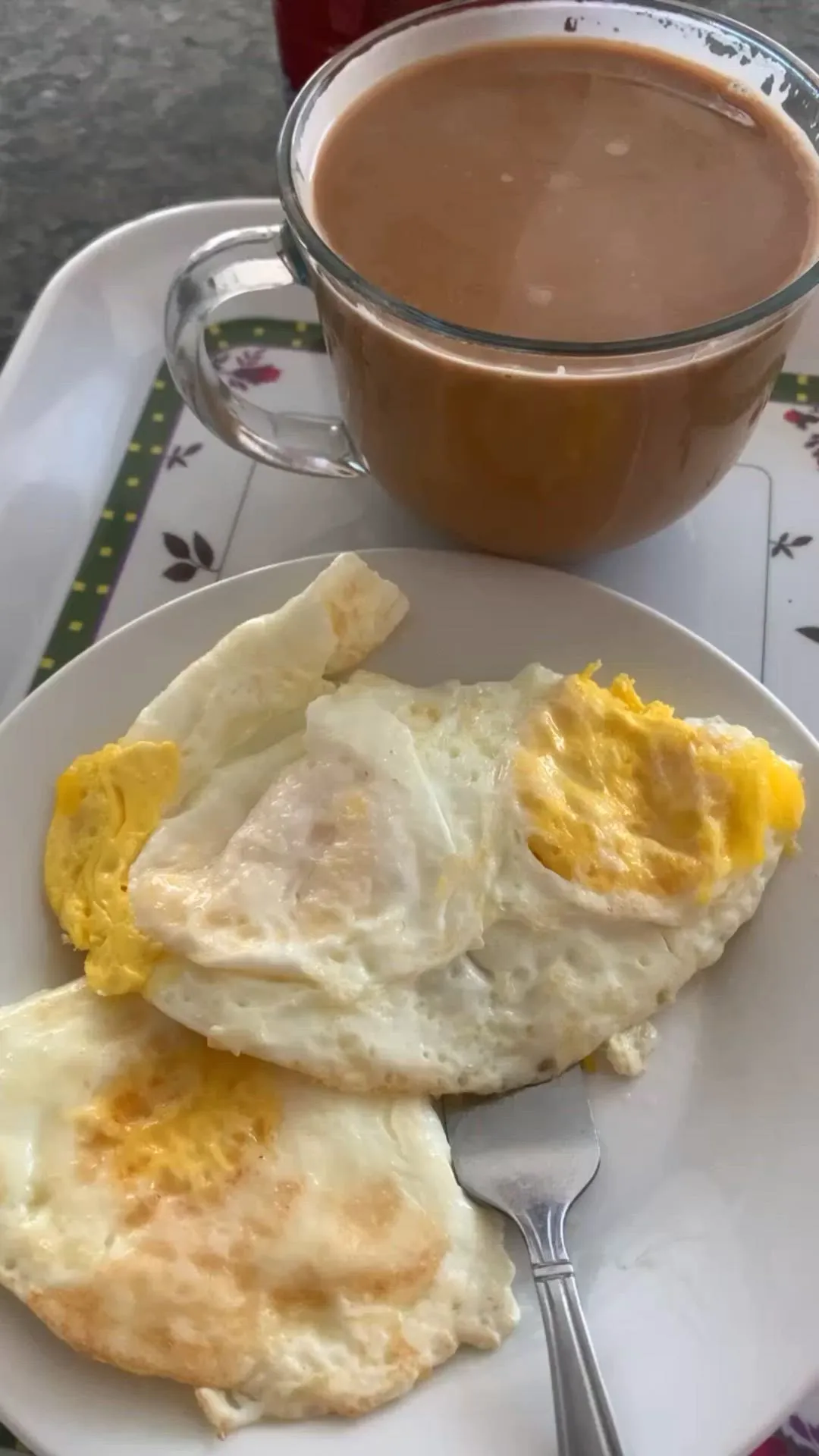 an omelet on a white plate next to a cup of coffee and spoon