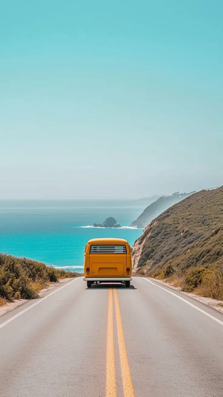 a yellow bus is driving down the road by the ocean in california, united states