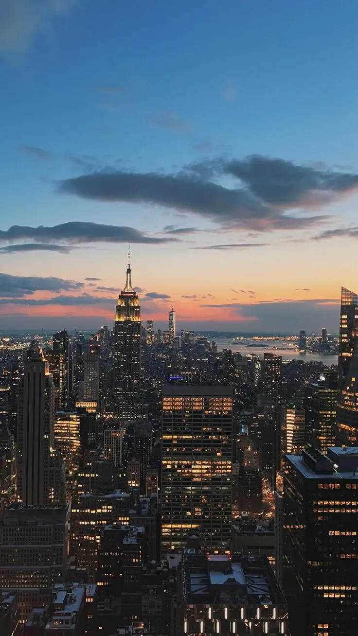 the city skyline is lit up at night, with skyscrapers in the foreground
