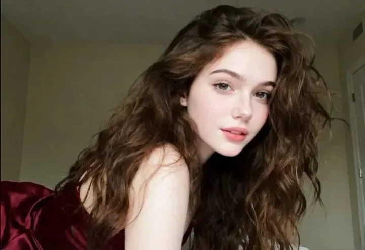 a young woman with long brown hair wearing a red dress and posing for the camera