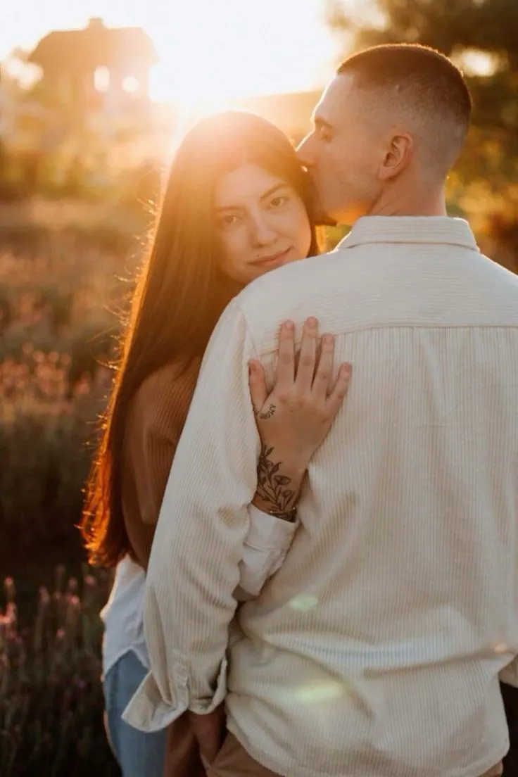 a man and woman embracing each other in front of the sun