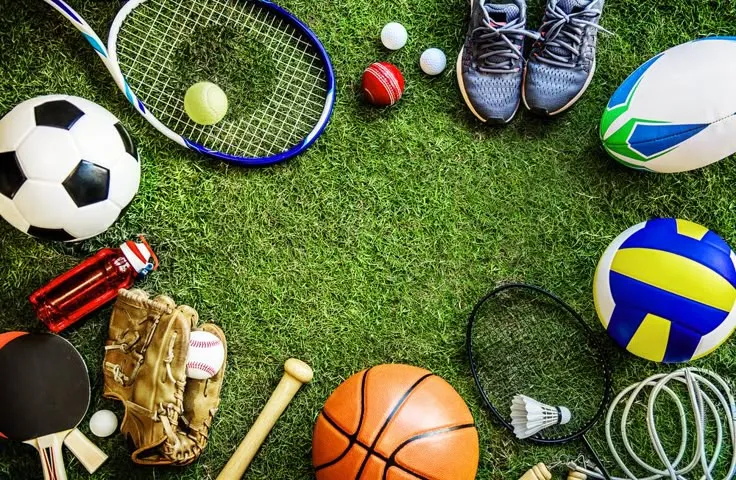 various sports equipment laid out on the grass, including tennis balls and racquets