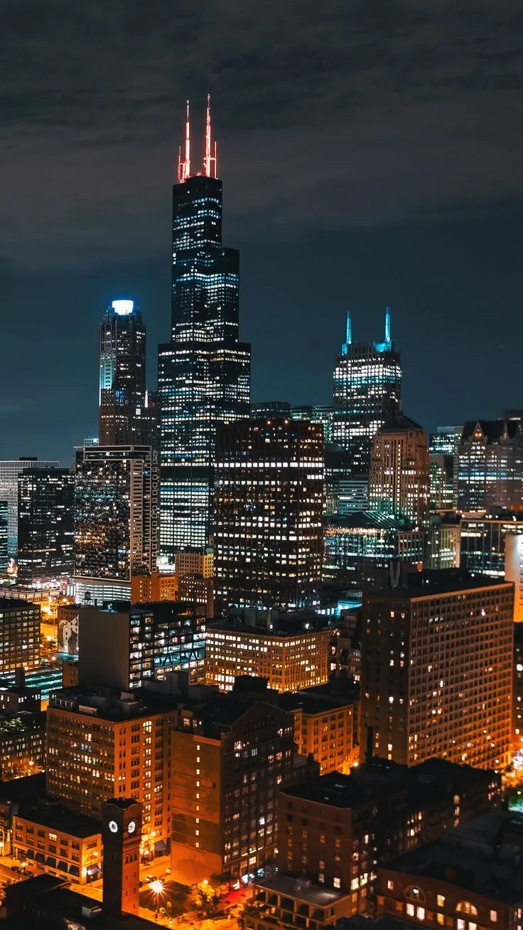 the city is lit up at night with bright lights on its buildings and skyscrapers