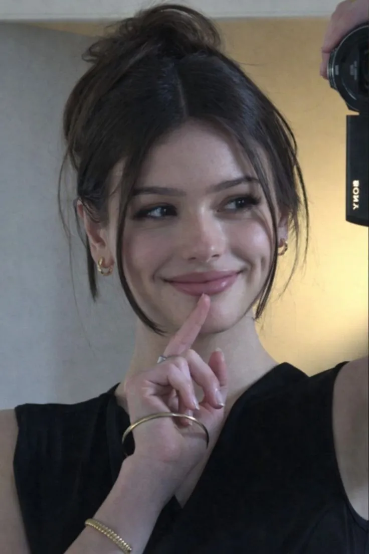 a woman is taking a selfie in front of a mirror with her finger on her lips