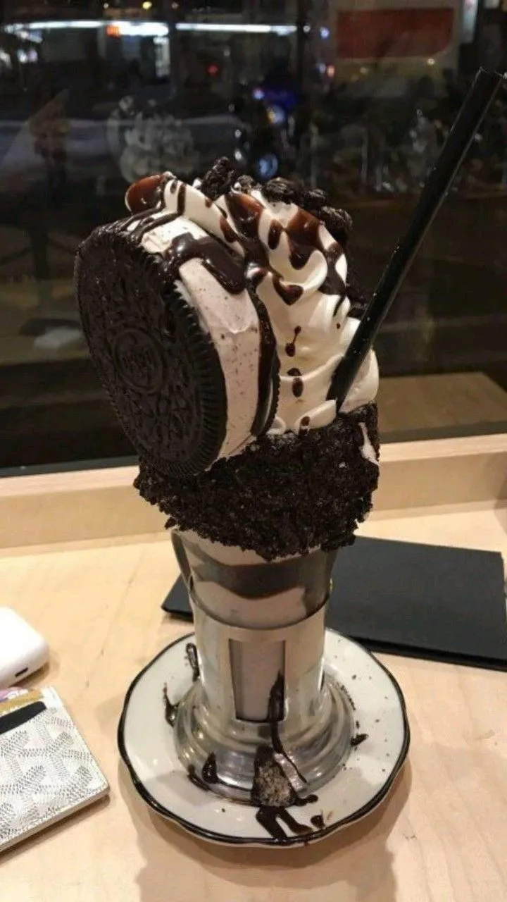 an ice cream sundae with chocolate and oreo cookies on top is sitting on a table