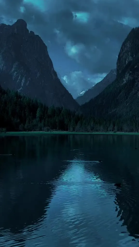the sky is reflecting in the water at night with clouds and trees on either side