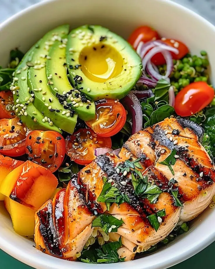 a white bowl filled with chicken, tomatoes, avocado and other veggies