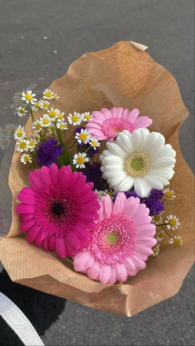 a bouquet of flowers sitting on top of a brown paper bag