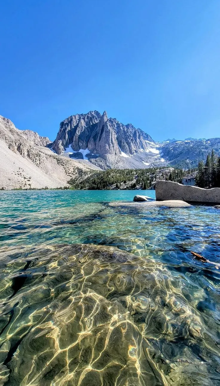 the water is crystal and clear with mountains in the background