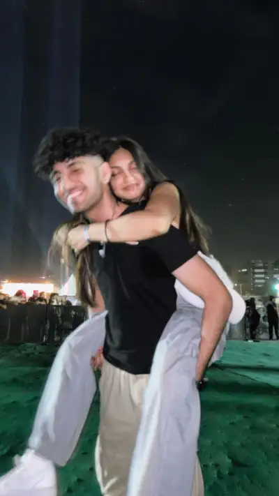 two people standing in the grass with their arms around each other