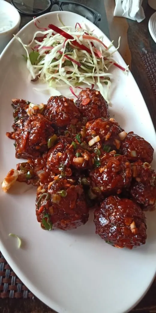 a white plate topped with meat covered in sauce and garnished with sprouts
