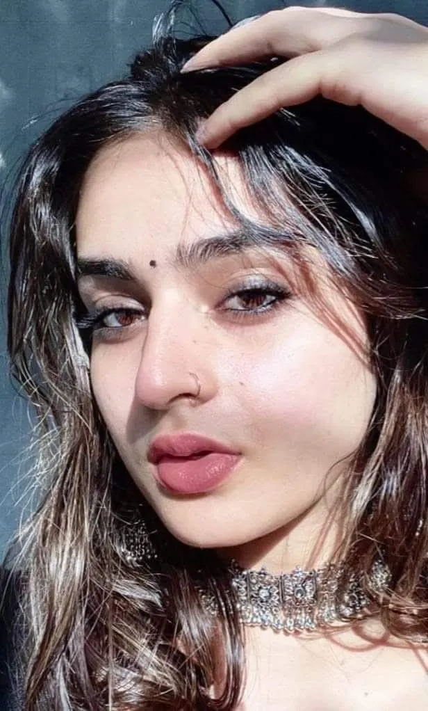 a close up of a person wearing a choker and posing with her hand on her head