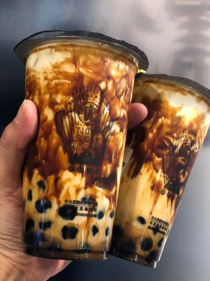 two coffee cups with brown and black designs on them are being held in front of the camera